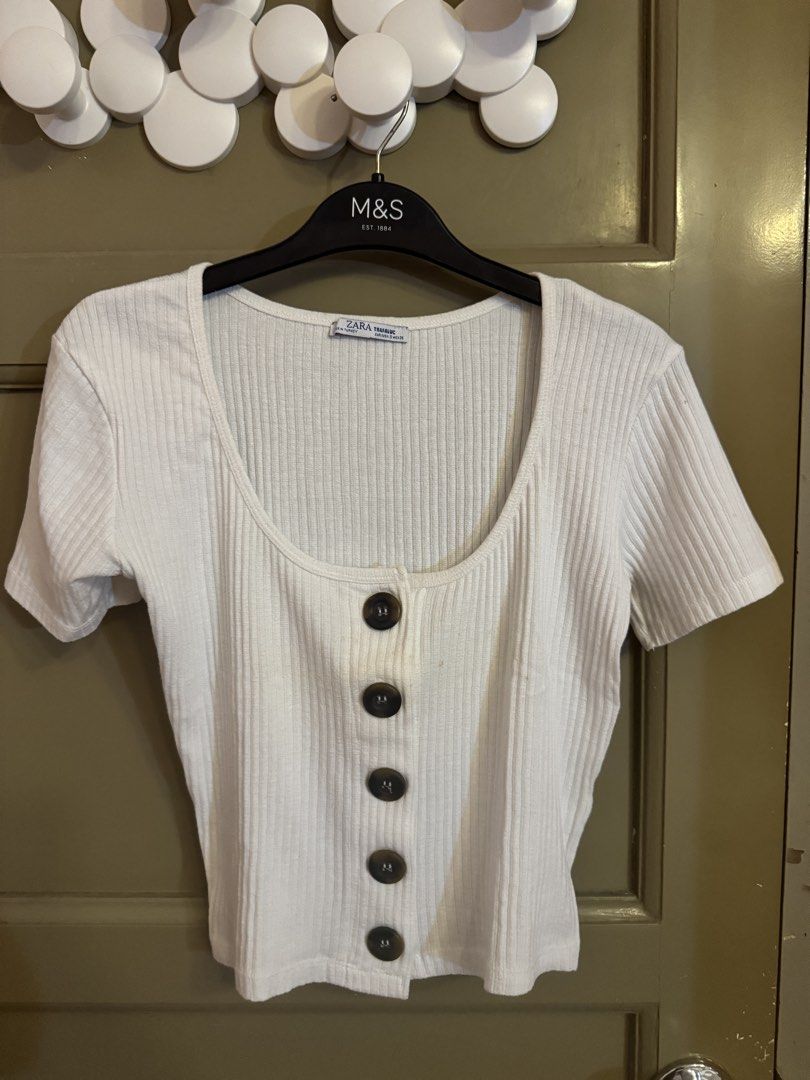 Zara Ribbed Button-Up White Top (Category: Blouses) located in Manila. Submitted by gabwie (Listing ID 1468406947, Image 1). Description: - Brand/Style: Zara Trafaluc white ribbed top - Size: S (EUR/USA S, MEX 26) - Details: Short sleeves, scoop neckline, dark tortoiseshell front buttons - Condition: Pre-loved with small yellowish stains near the button placket (please check pictures closely) - Yellowish stain can be removed with Zonrox — I can’t