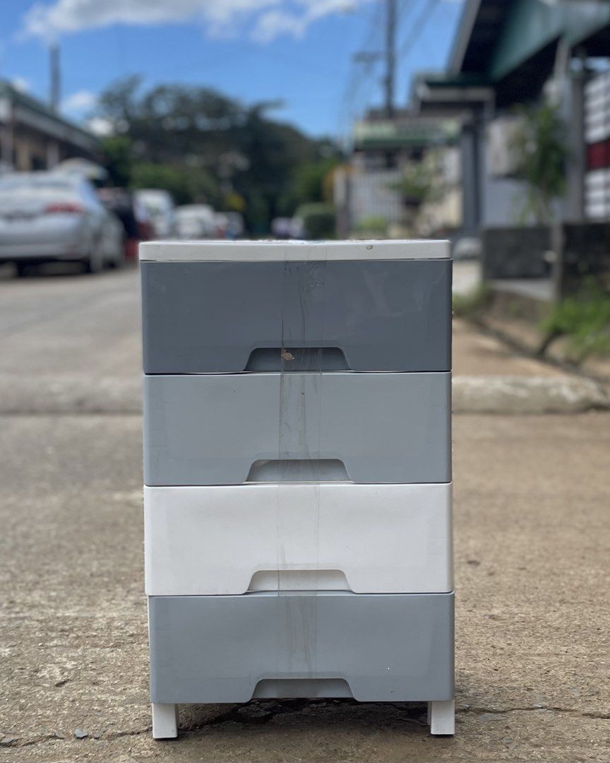 4-tier plastic storage drawer cabinet (Category: Shelves, Cabinets & Racks) located in Manila. Submitted by wassaup (Listing ID 1468518119, Image 2). Description: - 4-drawer plastic storage cabinet with cute small legs - Color: Grey (top, bottom, 2nd) and White (3rd) - Perfect for organizing clothes, toys, and small items in any room - Easy to wipe clean and maintain - Note: Has some minor dirt marks on the front middle part due to outdoor storag
