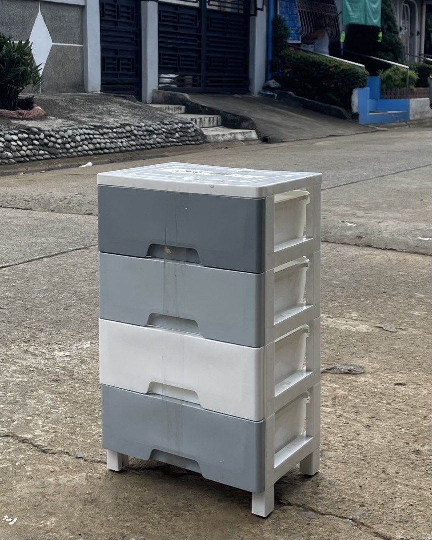 4-tier plastic storage drawer cabinet (Category: Shelves, Cabinets & Racks) located in Manila. Submitted by wassaup (Listing ID 1468518119, Image 1). Description: - 4-drawer plastic storage cabinet with cute small legs - Color: Grey (top, bottom, 2nd) and White (3rd) - Perfect for organizing clothes, toys, and small items in any room - Easy to wipe clean and maintain - Note: Has some minor dirt marks on the front middle part due to outdoor storag