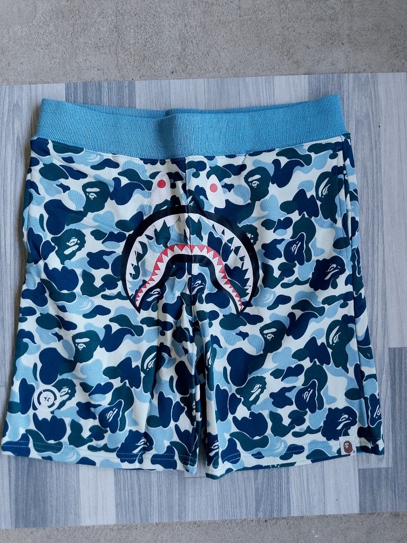 A Bathing Ape Bape Shark Camo Shorts (Category: Shorts) located in Batangas. Submitted by rafstaywitstaff_11 (Listing ID 1468585987, Image 3). Description: - Item: Bape Shark Camo Shorts - Design: Signature shark face graphic across the front - Colors: Available in various colors - Fit & Comfort: Elastic waistband with adjustable drawstring closure - Details: Woven logo tag on left hem with interior brand and size tags attached - Sizes: L and XL.