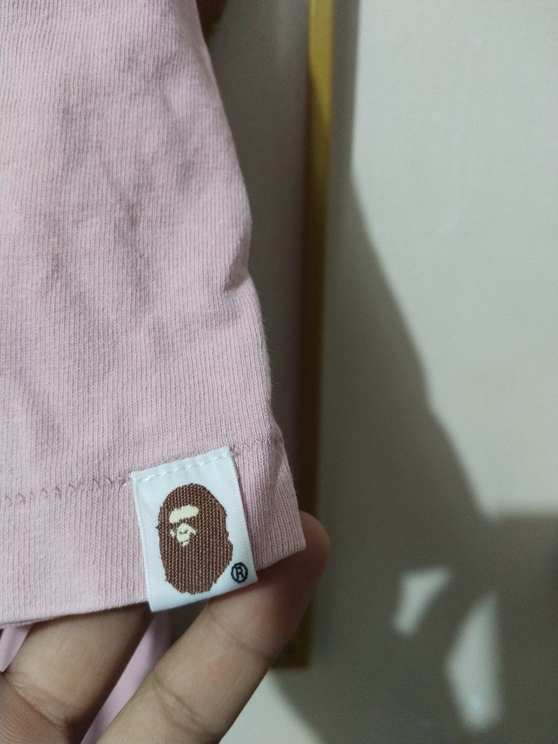 A Bathing Ape Pink T-Shirt XL (Category: Shirts) located in Manila. Submitted by bentong18188433 (Listing ID 1468617036, Image 3). Description: - Brand: A Bathing Ape (Bape) - Color: Pink - Design: Classic black ape head graphic with arched lettering on chest - Size: XL (collar tag attached) - Details: Signature small ape tag on the left sleeve - Fit: Regular fit, crewneck style - Condition: Excellent, ready to ship.
