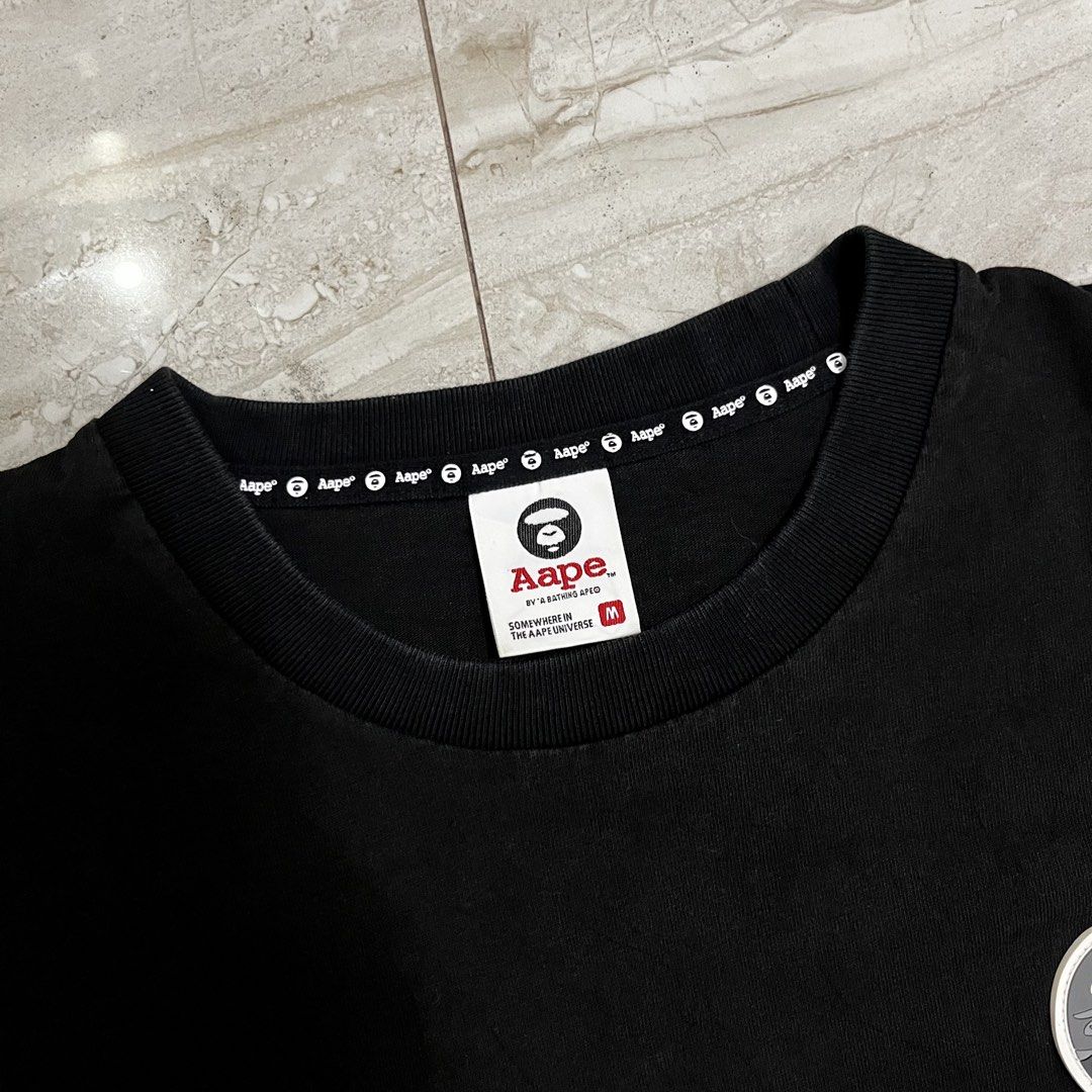 AAPE By A Bathing Ape Black Camo Tee (Category: Tshirts & Polo Shirts ) located in Polangui. Submitted by rodss7 (Listing ID 1468610742, Image 3). Description: - Brand: AAPE by A Bathing Ape - Color: Black with grey camo accent panel at the bottom hem - Size: M - Material: 100% Cotton (casual and comfortable) - Design: Classic round neckline with branded inner tape, round monkey logo patch on the left chest - Authenticity details: Size M tag at c