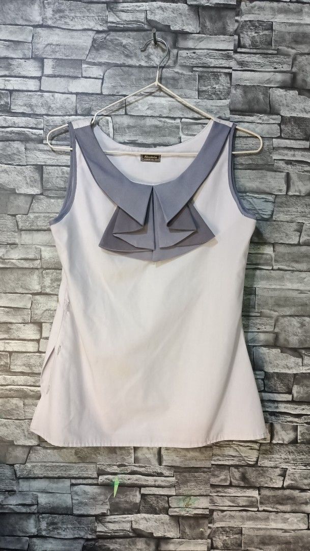 Absokuto White Sleeveless Blouse with Grey Ruffle Collar (Category: Sleeveless) located in Antipolo. Submitted by reahespiritu (Listing ID 1468642656, Image 1). Description: - Brand: Absokuto - Color: White with grey accents - Style: Sleeveless blouse with a distinct grey layered ruffle collar and matching arm trim - Closure: Convenient side zipper - Fabric: Lightweight and clean look - Versatility: Ideal for workwear, easily pairs with pants or 