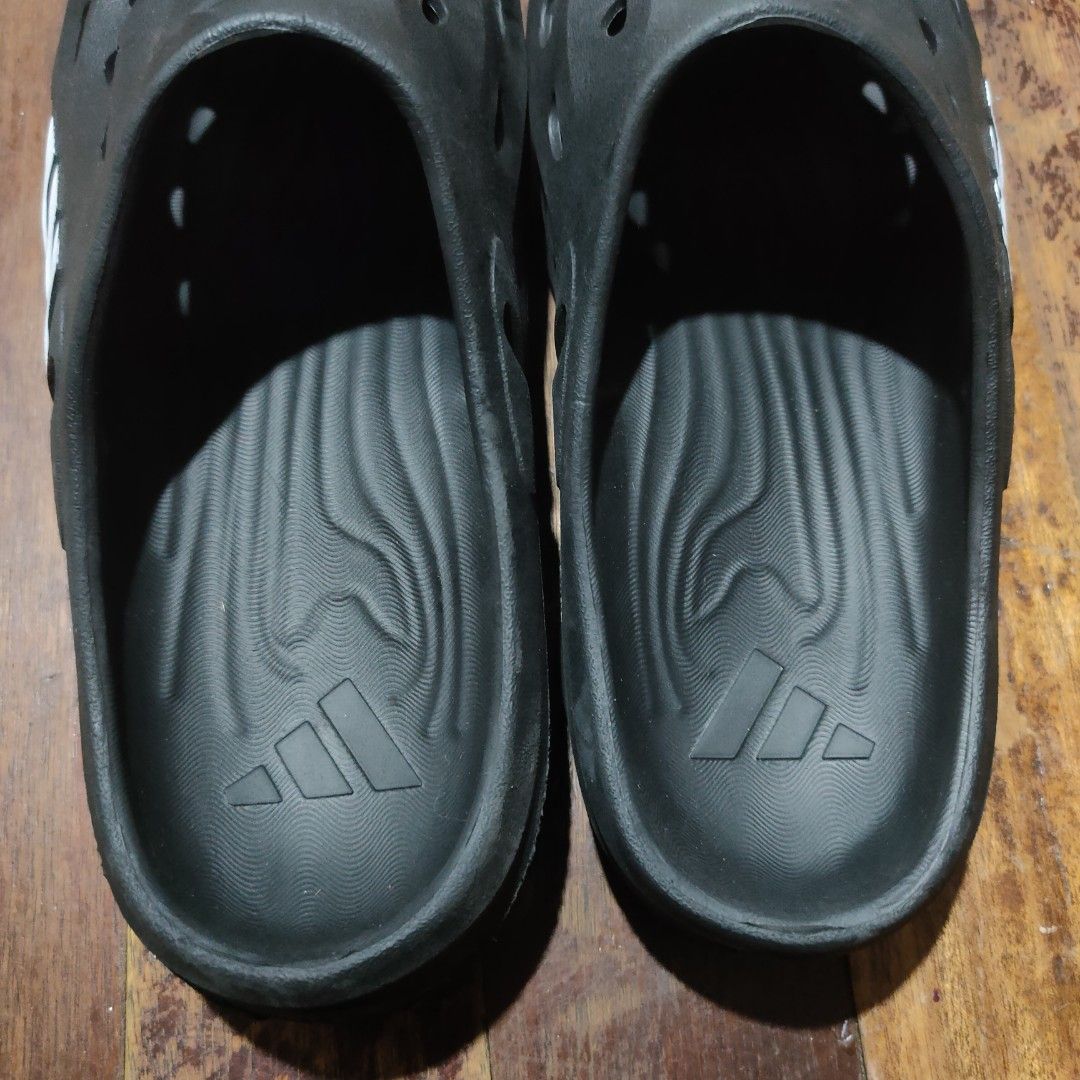 Adidas Adilette Clog Black Slides (Category: Slippers & Slides) located in Taguig. Submitted by actualizeboutique (Listing ID 1468521930, Image 3). Description: - Brand: Adidas - Style: Slip-on clog with ventilation holes - Color: Black with silver three-stripe branding - Features: Textured footbed and grooved rubber outsoles for better grip - Condition: Minor wear on soles from previous use - Ideal for: Casual everyday use, beach, or quick erran