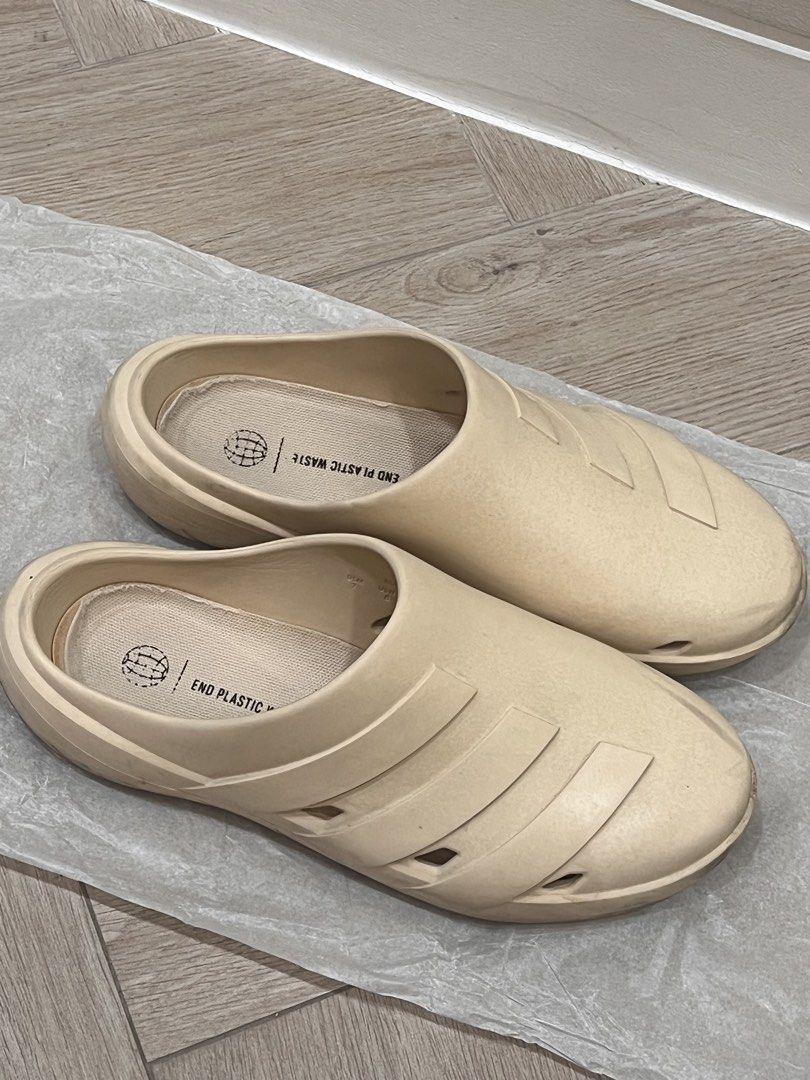 Adidas Adilette Clogs Beige (Category: Slippers & Slides) located in Quezon City. Submitted by adriangrafilo (Listing ID 1468620040, Image 2). Description: - Brand: Adidas - Style: Slip-on clogs - Color: Cream white - Features: Cutout stripes on sides, 'End Plastic Waste' text on insoles, woven fabric lining - Condition: Worn, with noticeable dirt on textured rubber outsoles and minor scuffs on the foam upper - Best for: Daily casual wear and eff