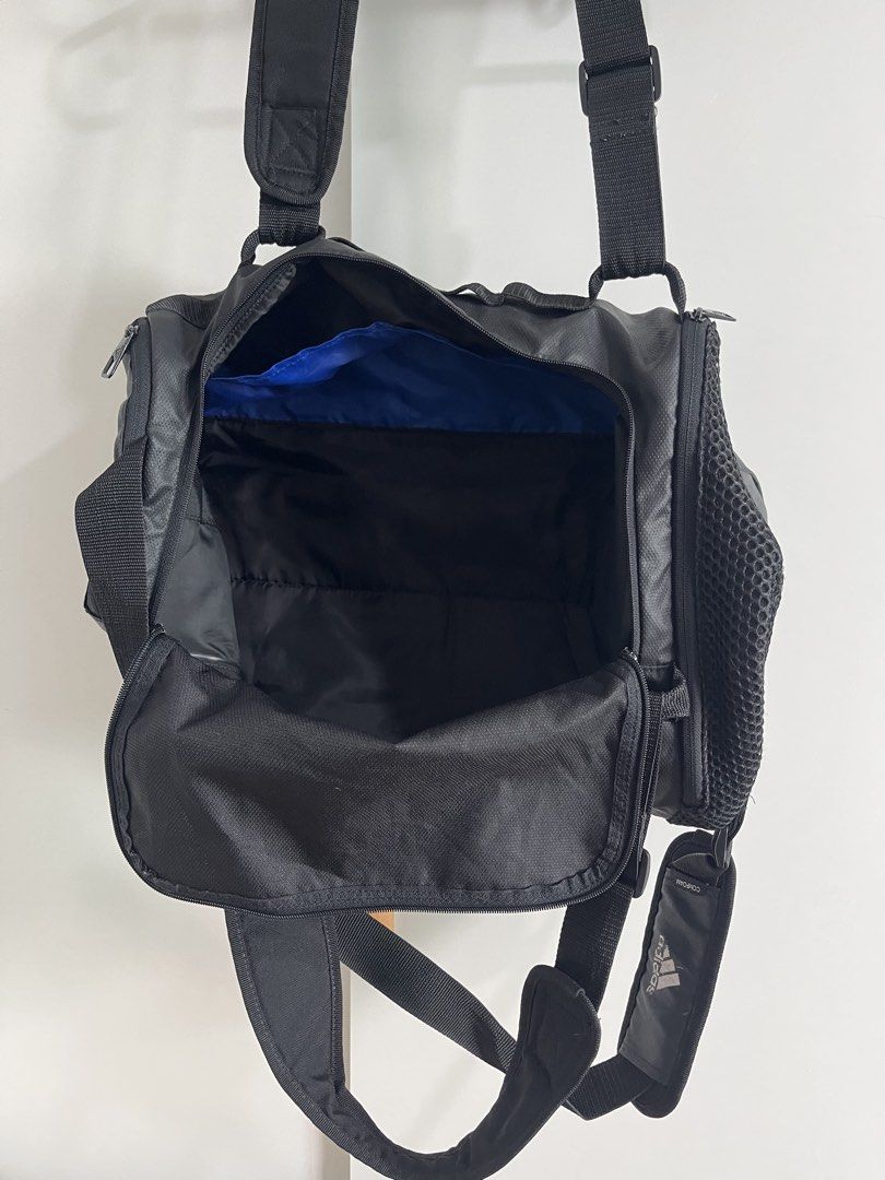 Adidas Black Duffel Gym Bag (Category: Sling Bags) located in Mandaluyong City. Submitted by unomarcelo001 (Listing ID 1468540667, Image 3). Description: - Authentic Black Adidas duffel bag - Durable, textured solid build with a clean interior and exterior - Dual carry handles and an adjustable padded shoulder strap with branding - Convenient side mesh pocket for quick access items - Spacious main zip compartment with a striking bright blue inner