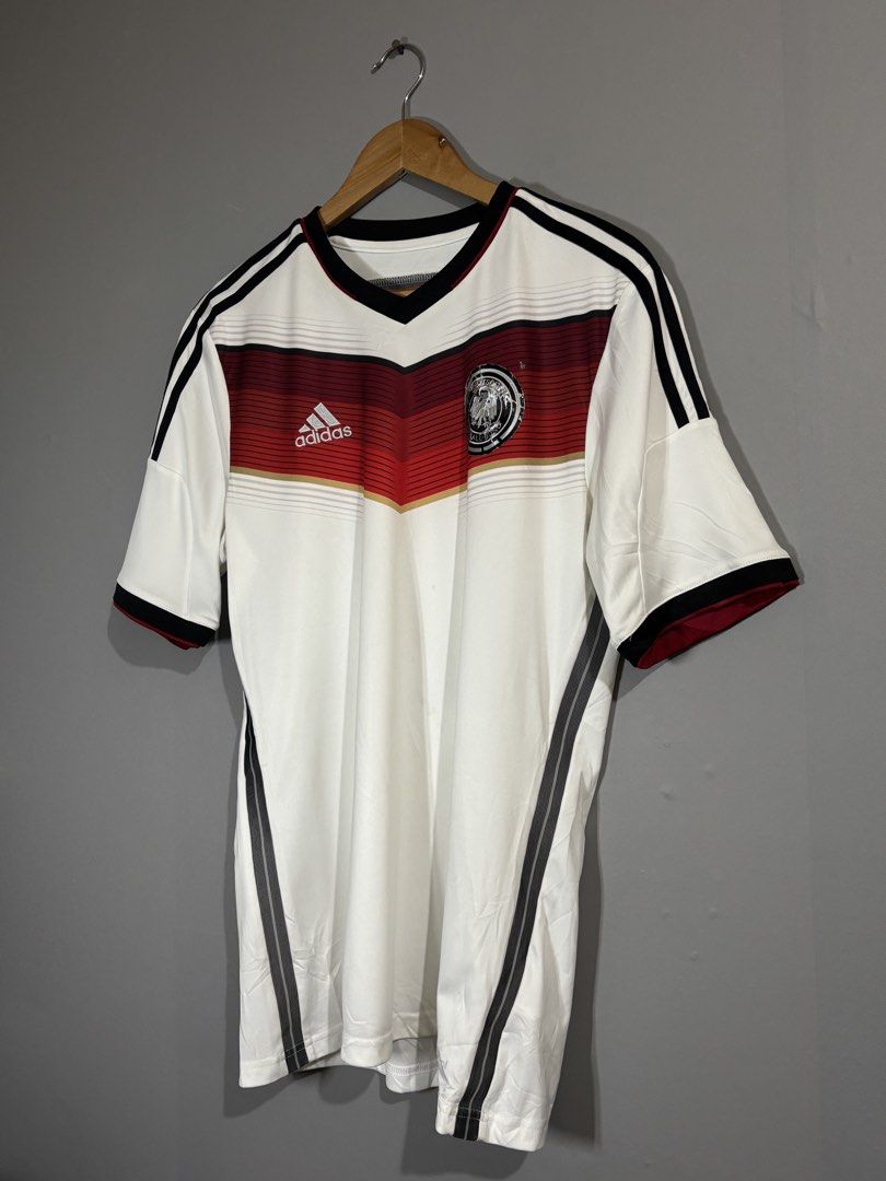 Adidas Germany Home World Cup Jersey (Category: Activewear) located in Butuan. Submitted by thriftheadsofficial (Listing ID 1468505808, Image 2). Description: - Official Adidas Germany home football jersey - Iconic black, red, and gold chest chevron graphic - Classic v-neck collar with black trim and shoulder stripes - Official licensed product tag intact - Standard fit short sleeve kit - Made in China.