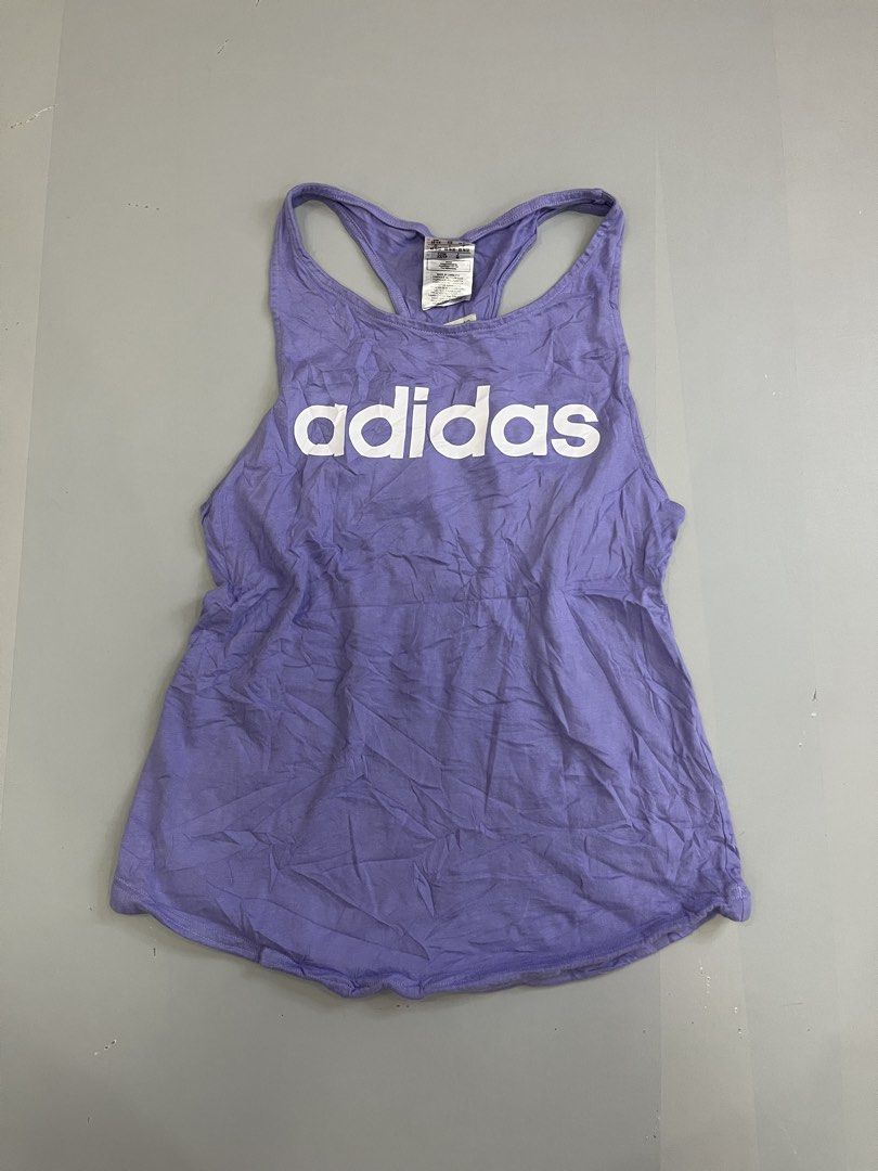 Adidas Purple Racerback Tank Top (Category: Activewear) located in Mabalacat. Submitted by aas_thriftfings (Listing ID 1468576996, Image 1). Description: - Brand: Adidas - Color: Purple - Style: Racerback tank top, casual athletic wear - Size: XS (with international equivalents on tag) - Design: Large white logo on the chest and smaller graphic on the upper back - Origin: Made in Cambodia - Condition: Excellent for workouts or daily wear.