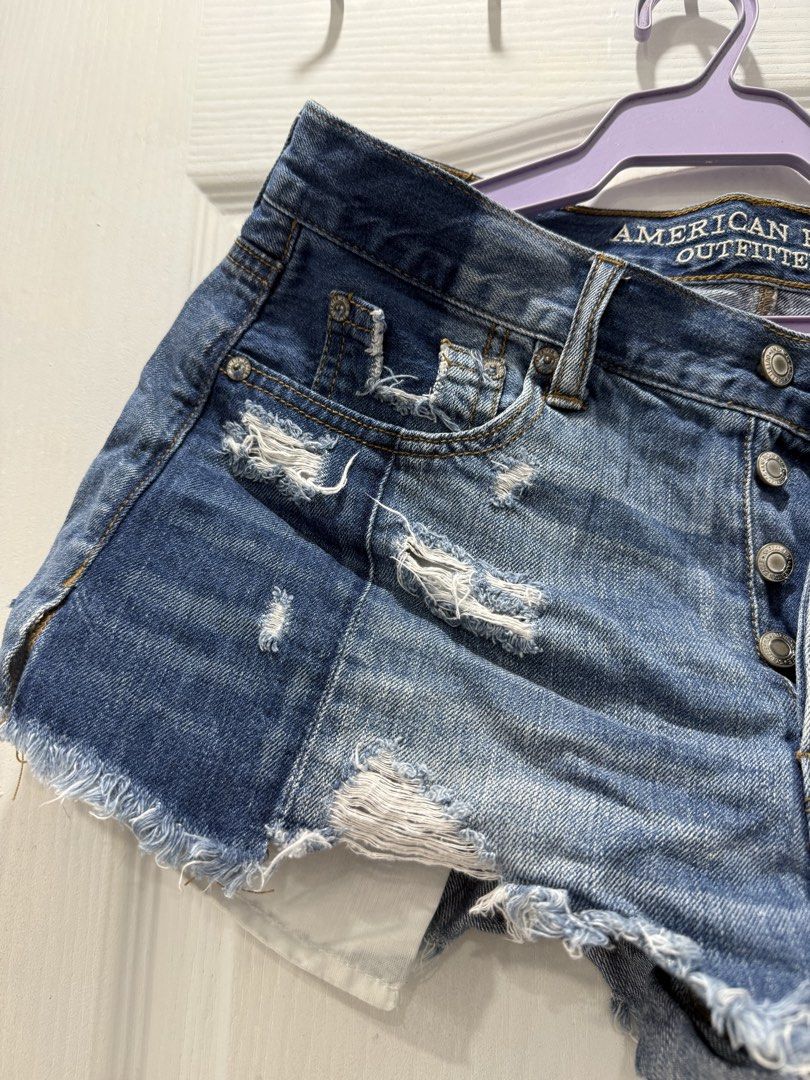 American Eagle Outfitters Distressed Denim Shorts (Category: Shorts) located in Manila. Submitted by prelov3dbysteph (Listing ID 1468550794, Image 3). Description: - Brand: American Eagle - Style: High-waisted denim shorts with button fly - Wash: Medium blue with heavy distressing - Details: Frayed raw hems and contrasting darker denim back patch pocket - Pockets: Classic five-pocket styling - Condition: Excellent, ready to wear.