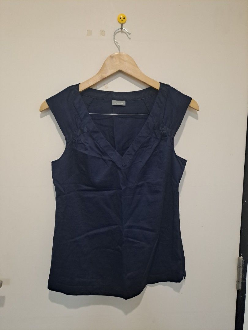 ANN TAYLOR NAVY BLUE (Category: Sleeveless) located in Manila. Submitted by joanbalde39643 (Listing ID 1468611399, Image 1). Description: The image displays a structured, sleeveless navy blue blouse featuring a wide, tailored V-neckline. The design is detailed with clean pleating at the shoulders and a classic panel accent down the center front..