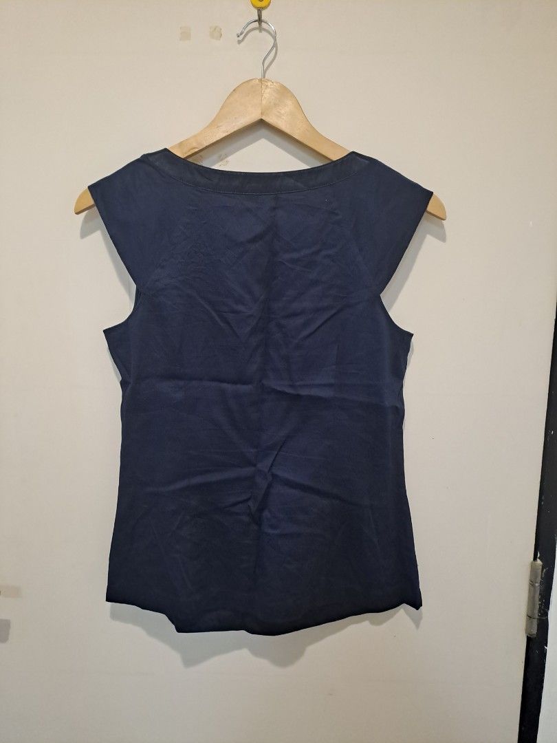 ANN TAYLOR NAVY BLUE (Category: Sleeveless) located in Manila. Submitted by joanbalde39643 (Listing ID 1468611399, Image 3). Description: The image displays a structured, sleeveless navy blue blouse featuring a wide, tailored V-neckline. The design is detailed with clean pleating at the shoulders and a classic panel accent down the center front..