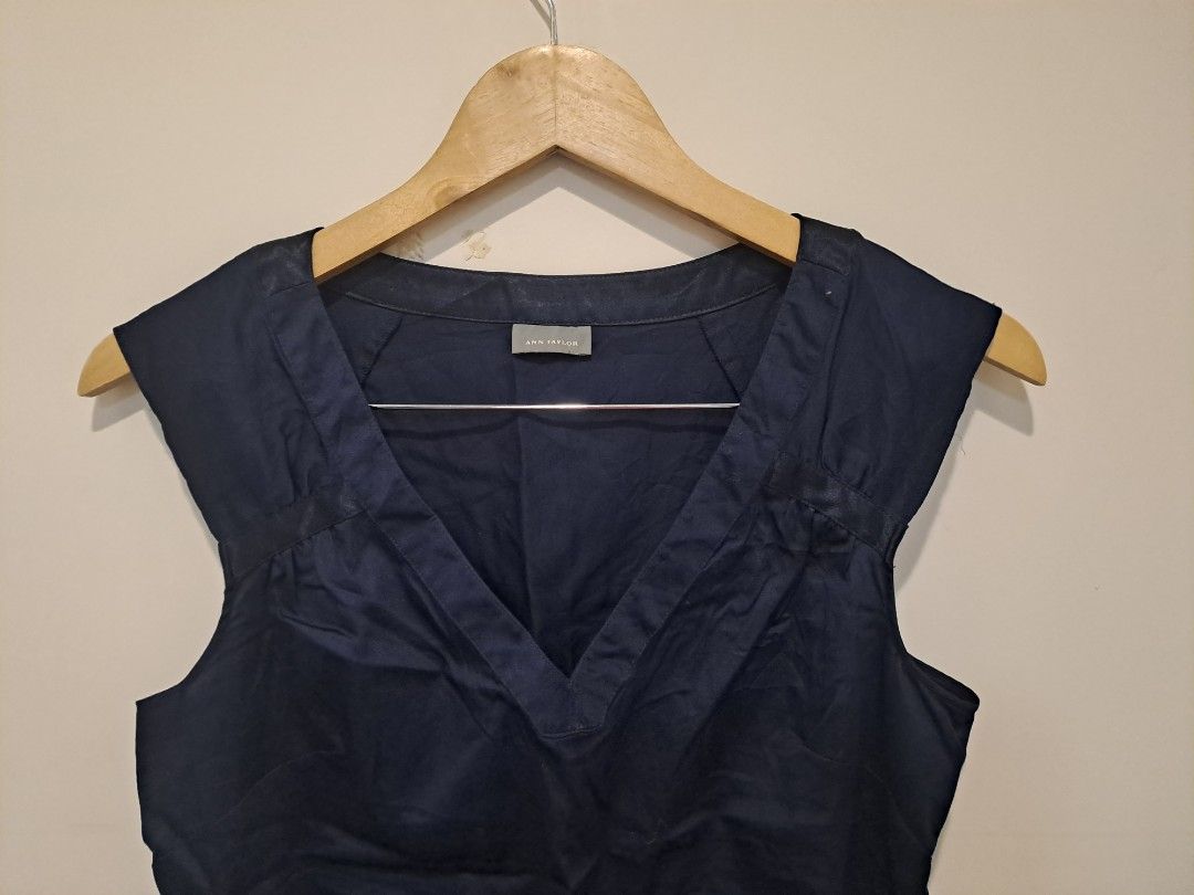 ANN TAYLOR NAVY BLUE (Category: Sleeveless) located in Manila. Submitted by joanbalde39643 (Listing ID 1468611399, Image 2). Description: The image displays a structured, sleeveless navy blue blouse featuring a wide, tailored V-neckline. The design is detailed with clean pleating at the shoulders and a classic panel accent down the center front..