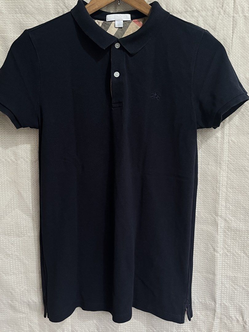 Authentic Burberry Polo Shirt (Category: Shirts) located in Davao. Submitted by aelane.listings (Listing ID 1468499976, Image 1). Description: Color: Black or dark blue Size: 14 Youth on tag, may fit XS-S adult Measurements: 16 1/2in x 25in - Iconic nova check pattern on inside collar and placket - Small embroidered equestrian knight on left chest - Two pearl-tone front buttons Short sleeves, ribbed cuffs and collar Condition: Well-used Clean dar