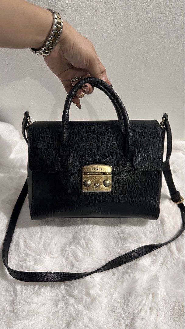 💯Authentic/Original Furla Metropolis Small Satchel Bag (Category: Luxury Bags & Wallets) located in Las Pinas. Submitted by allenscloset (Listing ID 1468624969, Image 1). Description: Minimal fading hardwares Brand: Furla Condition: Good Source: Japan Origin: Italy Style: Structured satchel / top-handle bag Color: Black with gold-tone metal hardware Features: Two rounded top handles, a front flap with a branded metal clasp, and a long shoulder s
