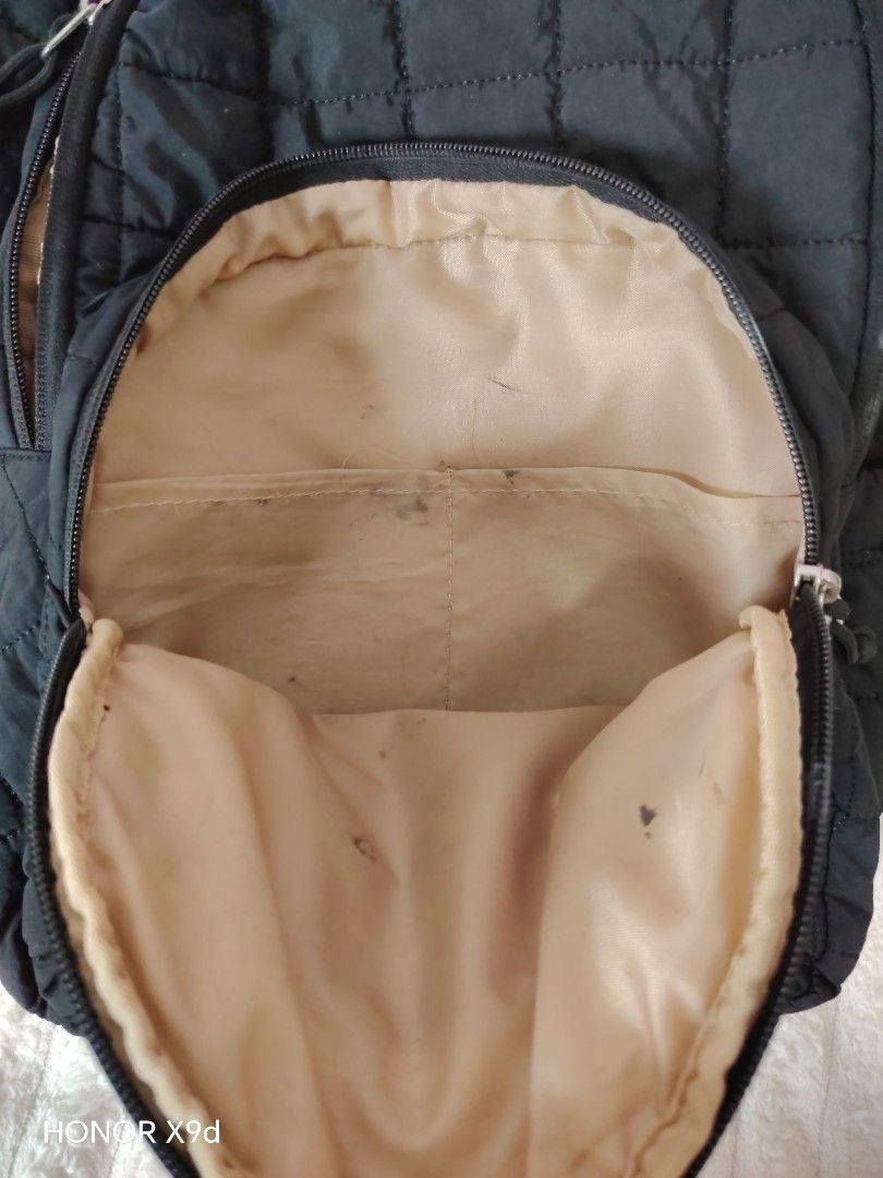Bagsmart Quilted Nylon Backpack with Front Zipper Pocket (Category: Backpacks) located in Mabalacat. Submitted by Jackikay.PreLoved (Listing ID 1468504601, Image 2). Description: Black quilted nylon backpack. Front pocket with zipper closure. Subtle metal badge reading BAG on the lower front section. Light beige interior lining featuring inner slip pockets. Shows visible stains and discoloration on the exterior base and inside lining..