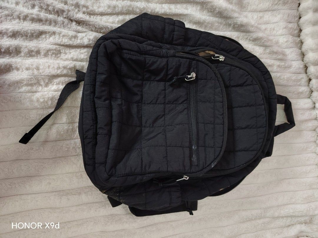 Bagsmart Quilted Nylon Backpack with Front Zipper Pocket (Category: Backpacks) located in Mabalacat. Submitted by Jackikay.PreLoved (Listing ID 1468504601, Image 1). Description: Black quilted nylon backpack. Front pocket with zipper closure. Subtle metal badge reading BAG on the lower front section. Light beige interior lining featuring inner slip pockets. Shows visible stains and discoloration on the exterior base and inside lining..