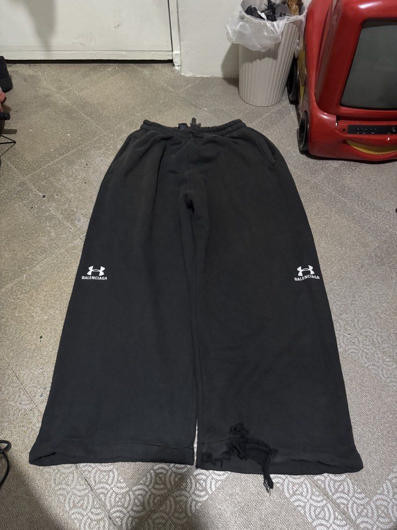 Balenciaga x Under Armour Sweatpants (Category: Joggers) located in Caloocan City. Submitted by eozilla (Listing ID 1468591680, Image 1). Description: - Brand: Balenciaga x Under Armour - Color: Black - Size: Large (L) - Fit: Wide leg with elastic waist and adjustable drawstring - Material: Premium cotton fleece, made in Portugal - Design: Under Armour logo prints and Balenciaga text on both lower legs - Details: Heavy distressing and raw hem on 