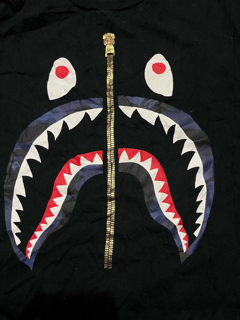 BAPE Shark Zip Graphic Tee Black Size M (Category: Tshirts & Polo Shirts ) located in Manila. Submitted by adzwilnams67005 (Listing ID 1468656423, Image 2). Description: BAPE graphic t-shirt in black. Iconic shark face print on the front with a gold zipper graphic down the center. Classic A Bathing Ape neck tag and wash label attached. Size medium, standard fit. 100% cotton material. Good streetwear staple. Bape shark ‎ ‎Size M on tag ‎Dimes:21.5