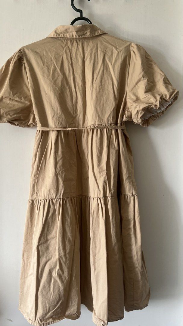 Beige Collared Puff Sleeve Tiered Dress (Category: Dresses) located in Taguig. Submitted by xkmanzano078817 (Listing ID 1468511139, Image 3). Description: Beige dress with a sharp shirt collar and short puff sleeves. Button-down front placket with two buttons visible. Includes a matching fabric tie belt at the waist. Skirt falls in a tiered, flared silhouette. Lightweight cotton-blend fabric. Length hits above the knee..