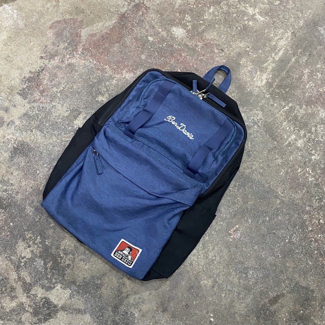 Ben Davis Blue Black Backpack (Category: Backpacks) located in Quezon City. Submitted by mgc_thriftshop (Listing ID 1468688814, Image 2). Description: - Brand: Ben Davis - Color: Blue and black - Material: Durable canvas-like fabric - Design details: Embroidered script logo and iconic gorilla patch - Features: Multiple compartments with branded metal zippers, padded straps, and top carry handle - Condition: Excellent, ideal for school or daily co