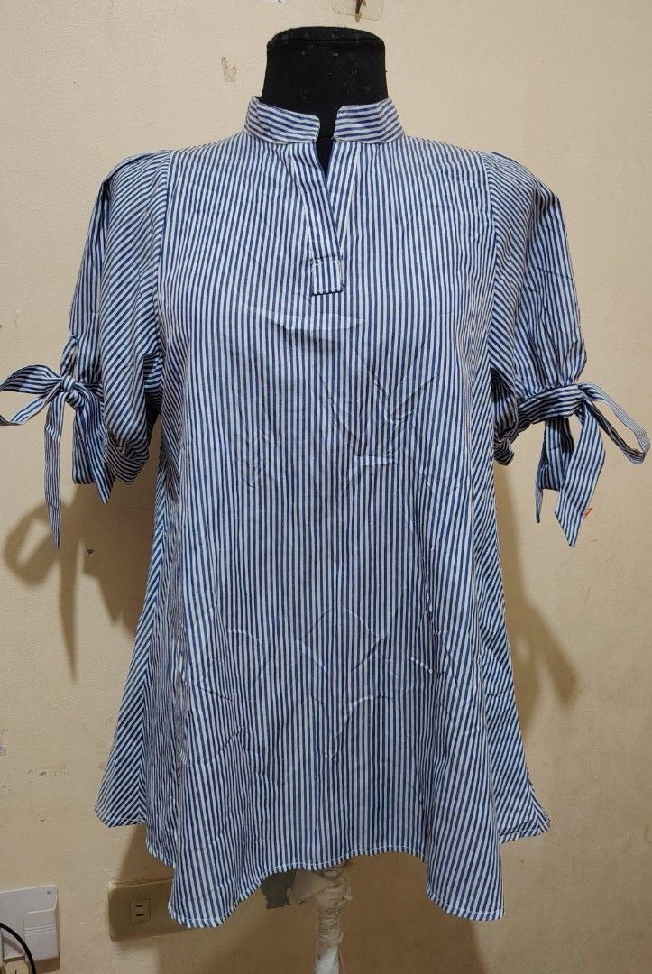 Blue and White Striped Blouse with Bow Sleeves (Category: Blouses) located in Manila. Submitted by forthriftstorewarriors (Listing ID 1468537397, Image 1). Description: - Design: Blue and white vertical stripes with a stand collar and V-slit - Sleeves: Short puff sleeves with cute tie-up ribbon bow cuffs - Fit: Loose and relaxed body fit for all-day comfort - Material: Lightweight and breathable fabric - Versatility: Perfect for casual outings or