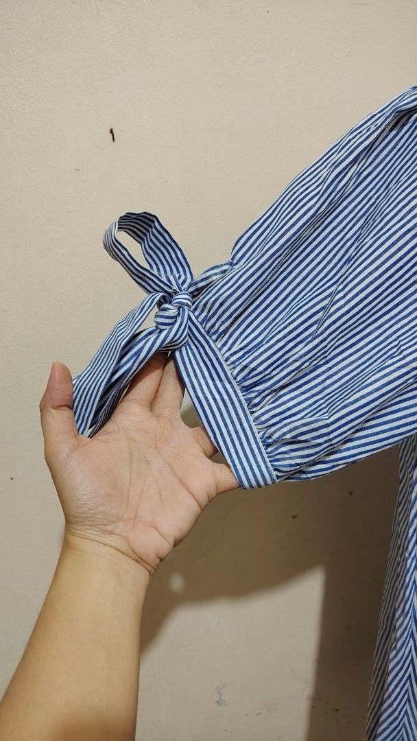 Blue and White Striped Blouse with Bow Sleeves (Category: Blouses) located in Manila. Submitted by forthriftstorewarriors (Listing ID 1468537397, Image 2). Description: - Design: Blue and white vertical stripes with a stand collar and V-slit - Sleeves: Short puff sleeves with cute tie-up ribbon bow cuffs - Fit: Loose and relaxed body fit for all-day comfort - Material: Lightweight and breathable fabric - Versatility: Perfect for casual outings or