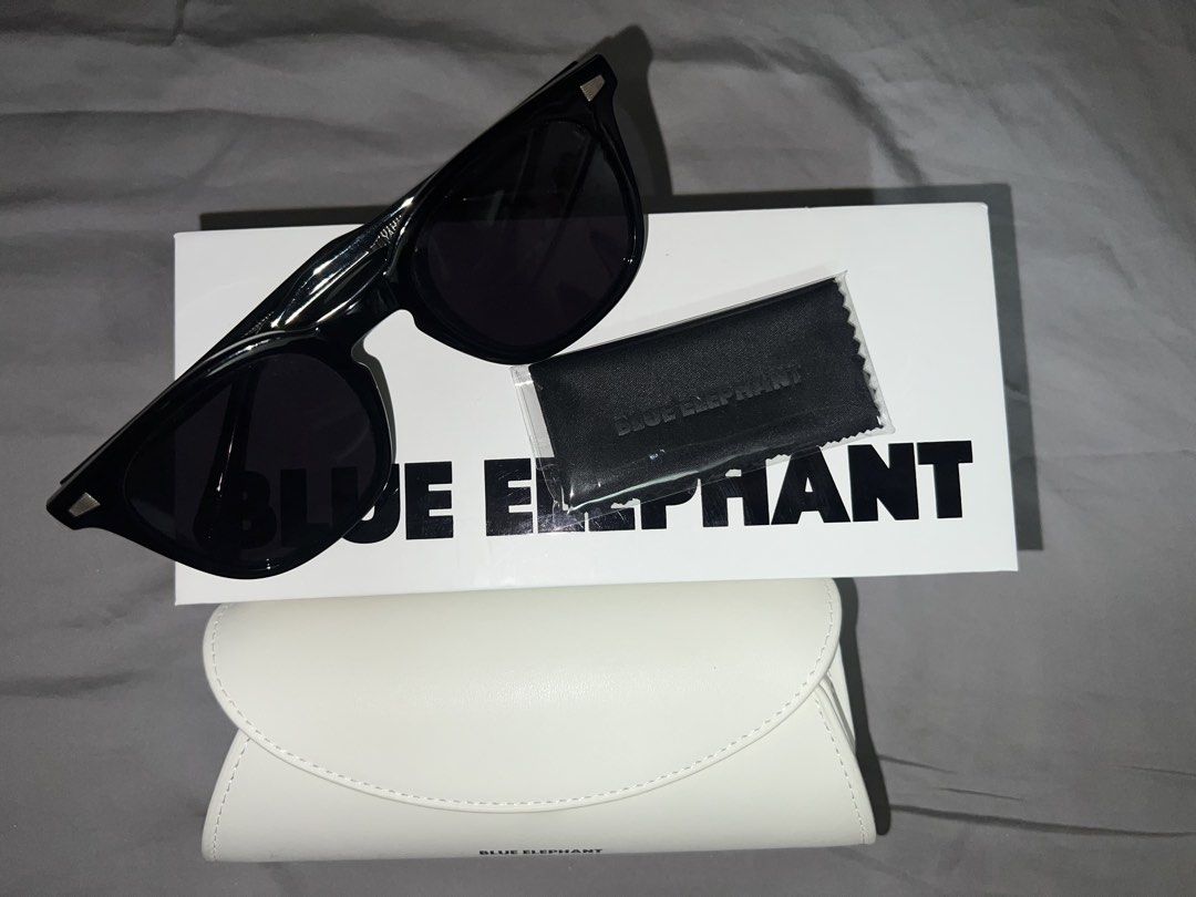 Blue Elephant sunglasses in black with white case and box (Category: Sunglasses & Eyewear) located in Manila. Submitted by wynnergy (Listing ID 1468587366, Image 3). Description: - Brand: Blue Elephant (Authentic) - Condition: Brand new, never worn - Color/Style: Glossy black frames with dark tinted lenses and textured metal arm details - Inclusions: Original white branded leather case, outer cardboard box, and unopened cleaning cloth - Perfect f