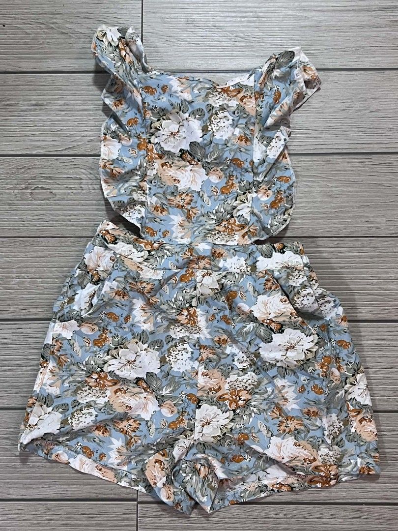 Blue floral romper with ruffle straps and open back (Category: Rompers) located in San Jose del Monte. Submitted by Skin_Care2022 (Listing ID 1468674824, Image 3). Description: - Style: Blue romper with white and orange floral print - Neckline & Straps: Square neckline with playful ruffled shoulder straps - Back Design: Open back with adjustable crisscross tie straps - Features: Functional side pockets - Fabric: Lightweight and breathable, ideal 