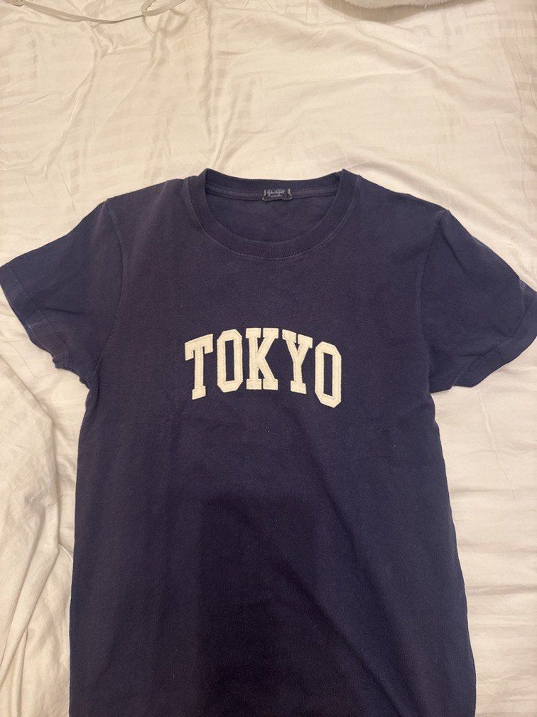 Brandy Melville Tokyo Navy Blue Tee (Category: Shirts) located in Mandaluyong City. Submitted by izabelly (Listing ID 1468656316, Image 1). Description: - Brand: Brandy Melville - Color: Navy blue with white 'TOKYO' block lettering - Fit: Easy everyday fit, short sleeves, crew neck - Material: Soft and comfortable cotton - Condition: Good, with slight wear around the collar - Style: Versatile basic that goes with everything.