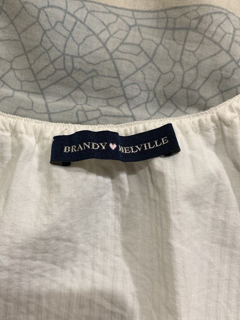 Brandy Melville White Button-Up Top (Category: Blouses) located in Malolos. Submitted by luvvtinx (Listing ID 1468592241, Image 3). Description: LAST PRICE Brand: Brandy Melville - Color: White - Style: Cap sleeve, button-down front with lace trim and vertical paneling - Fit: Cropped, fits small - Material: Lightweight cotton with subtle texture - Condition: Great everyday piece, easy to style with high-waisted shorts or jeans.