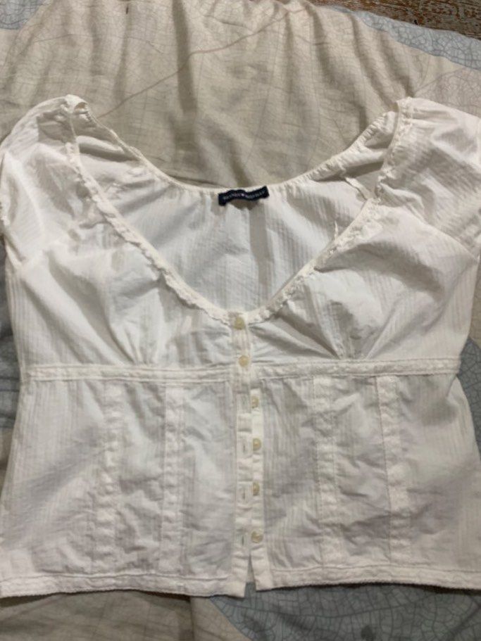 Brandy Melville White Button-Up Top (Category: Blouses) located in Malolos. Submitted by luvvtinx (Listing ID 1468592241, Image 2). Description: LAST PRICE Brand: Brandy Melville - Color: White - Style: Cap sleeve, button-down front with lace trim and vertical paneling - Fit: Cropped, fits small - Material: Lightweight cotton with subtle texture - Condition: Great everyday piece, easy to style with high-waisted shorts or jeans.
