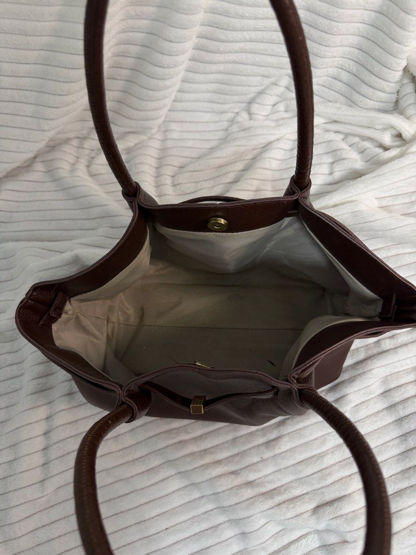 Brown Pebbled Leather Tote Bag with Gold Hardware (Category: Tote Bags) located in Rizal. Submitted by kianapreloves (Listing ID 1468590366, Image 3). Description: - Material: Rich brown textured leather - Handles: Double top handles for easy carrying - Details: Chic center front strap with a small gold-tone metal accent - Closure: Open top design with a secure magnetic snap - Interior: Light-colored patterned fabric lining with a roomy compartme