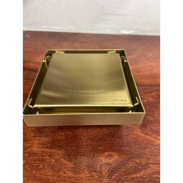 Brushed Gold Stainless Steel Square Floor Drain (Category: Bathroom & Kitchen Fixtures) located in Manila. Submitted by mightytiger_4bb6fd (Listing ID 1468616685, Image 3). Description: - Material: Heavy-duty stainless steel - Finish: Modern brushed gold - Design: Square shape with minimalist look - Includes: Outer frame, solid cover plate, slotted strainer insert, and circular hair catcher grate - Condition: Brand new, unused hardware left over 