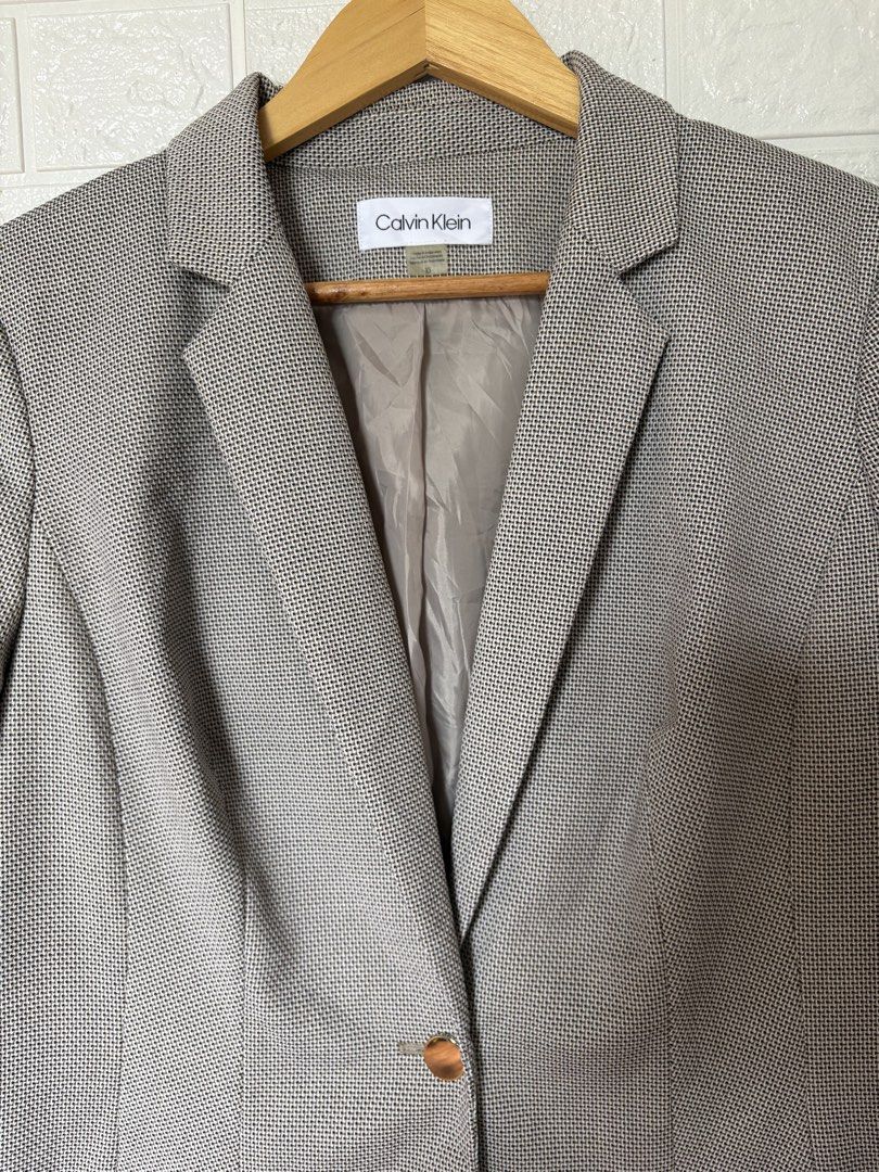 Calvin Klein Blazer (Category: Coats, Jackets and Outerwear) located in Batangas. Submitted by purple_and_orange (Listing ID 1468512041, Image 3). Description: - Brand: Calvin Klein - Size: 10 - Color/Pattern: Textured grey - Style: Single-button closure, notched lapels, and structured shoulders - Details: Two front patch pockets with subtle CK branding on the left pocket - Interior: Fully lined in light grey-taupe - Origin: Made in Indonesia - C