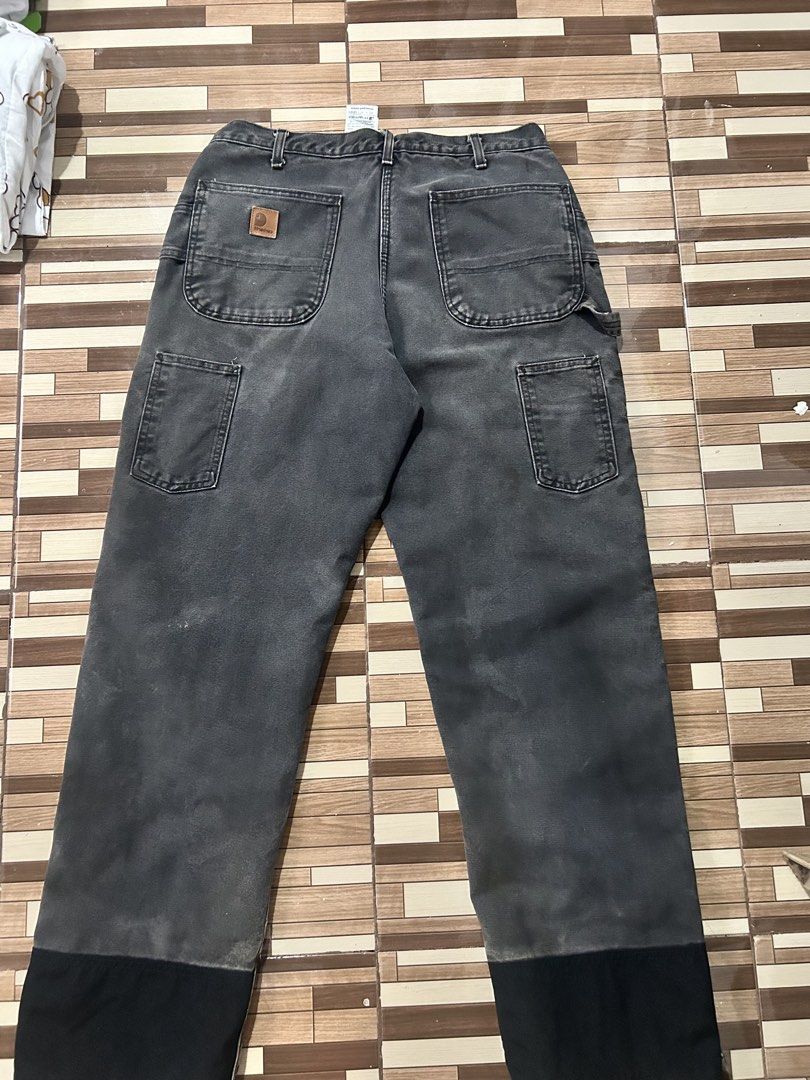 Carhartt Double Front Work Pants Black (Category: Jeans) located in Caloocan City. Submitted by wadxxx (Listing ID 1468594341, Image 2). Description: - Brand: Carhartt - Style: Double front work pants in black duck canvas - Condition: Faded wash with natural wear, authentic paint splatters, and slight hem fraying - Features: Heavy-duty cotton fabric, double knees, multiple utility pockets, and hammer loop - Details: Branded rivets and button clos