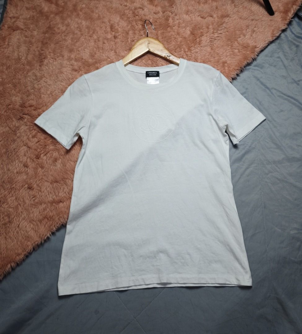 CHANEL WHITE TEES (Category: Luxury Apparel) located in Imus. Submitted by eykc01 (Listing ID 1468522579, Image 1). Description: -EUC-LIKE NEW -SMALL ON TAG -ARMPT-ARMPT: 14 INCHES -LENGHT: 23.5 INCHES **This item is an authentic Chanel Uniform Short-Sleeve T-Shirt, featuring a subtle, tonal embroidered interlocking CC logo centered on the chest.