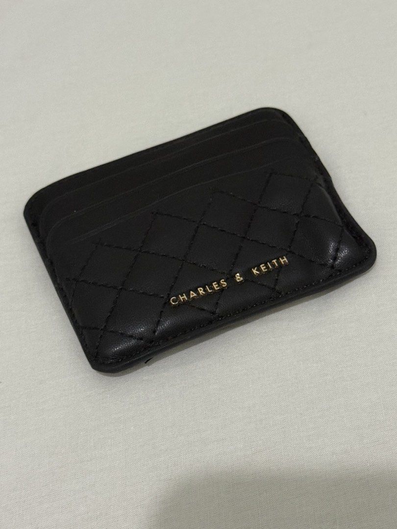 Charles & Keith Quilted Black Card Holder (Category: Wallets & Card holders) located in Mandaluyong City. Submitted by trovebya (Listing ID 1468586410, Image 1). Description: - Brand: Charles & Keith - Color: Classic Black - Design: Quilted front pattern with a smooth back finish - Hardware: Elegant gold logo lettering stamped in the middle - Storage: Multiple card slots on both sides - Size: Compact and slim, fits easily into pockets and micro b