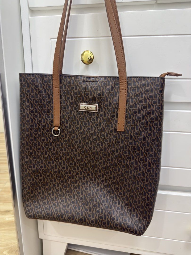 CLN Monogram Tote Bag Brown Tan (Category: Tote Bags) located in Manila. Submitted by chi.declutter (Listing ID 1468517485, Image 1). Description: - Brand: CLN - Design: Brown tote bag with all-over CLN monogram print and gold-tone front logo plate - Straps: Comfortable tan shoulder straps - Closures: Secure zip top closure with an extra magnetic snap button - Interior: Silky patterned fabric lining with built-in zipped compartments - Versatility