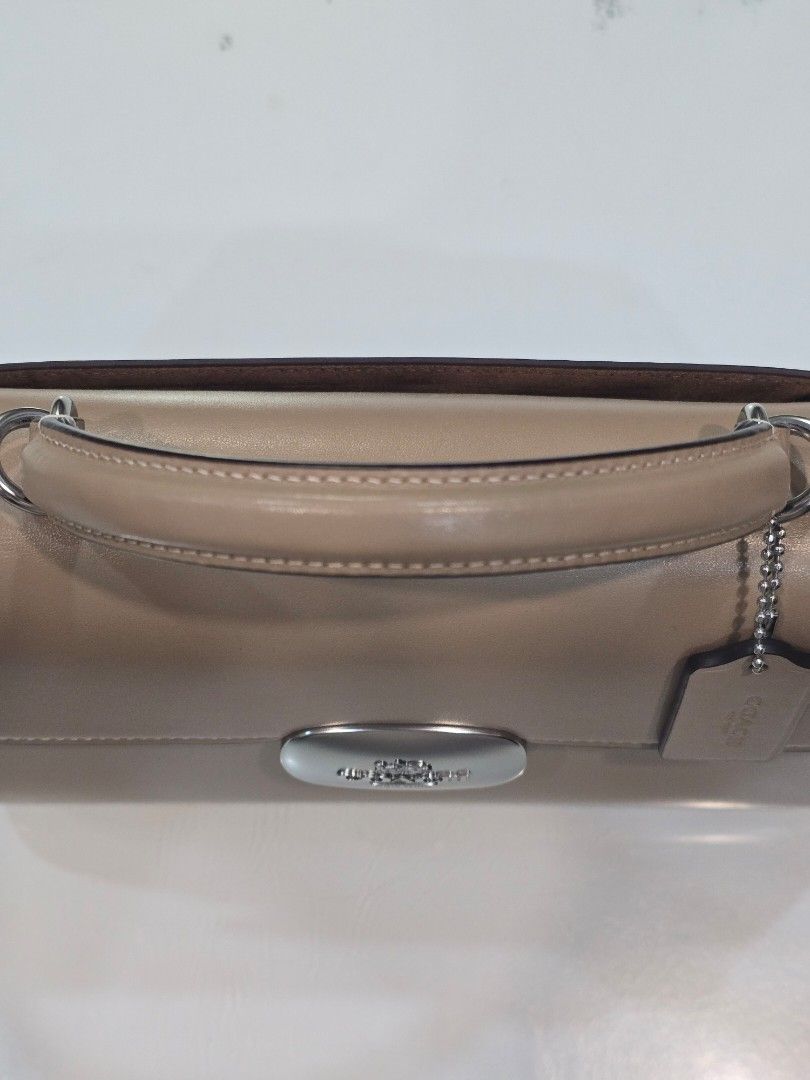 Coach Eliza top handle (Category: Luxury Bags & Wallets) located in Imus. Submitted by chie0308 (Listing ID 1468693117, Image 3). Description: Original Coach Eliza top handle in taupe color with silver hardware and magnetic closure. Top handle attached, plus an adjustable crossbody strap included. Interior lined with brown suede fabric, featuring a zippered compartment. Includes original white Coach dust bag and care booklet. Clean structure, pri