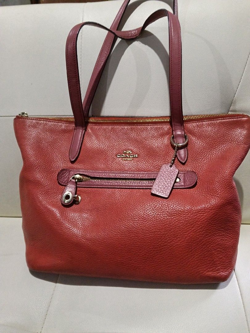 Coach Red Leather Tote Bag (Category: Luxury Bags & Wallets) located in Manila. Submitted by zenbear_6b2d8a (Listing ID 1468711247, Image 1). Description: - Brand: Coach - Material: Red pebbled leather with gold-tone hardware - Design: Pink double shoulder straps, front zip pocket with tassel pull, and hanging leather hangtag - Closure & Interior: Secure top zip closure, red fabric lining with multiple slip pockets and one zippered compartment - 