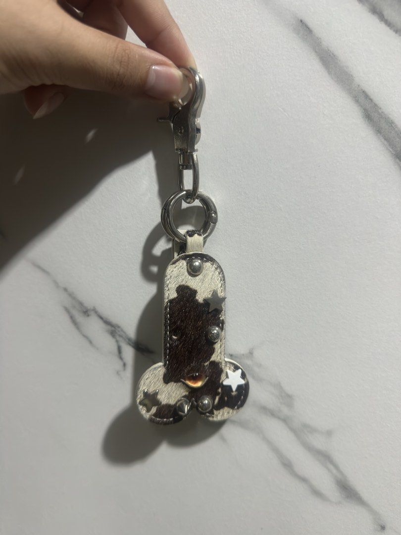 Cow print leather phallic novelty keychain with star studs (Category: Charms) located in Baguio. Submitted by miss_misery (Listing ID 1468565207, Image 1). Description: - Edgy novelty pen!s keychain and bag charm - Made in Vietnam, bought in Ho Chi Minh - Made with stylish black and white cow print leather/calf hair - Decorated with silver star studs, metal ball studs, and spike hardware - Features a built-in metal clip and split ring for keys - 