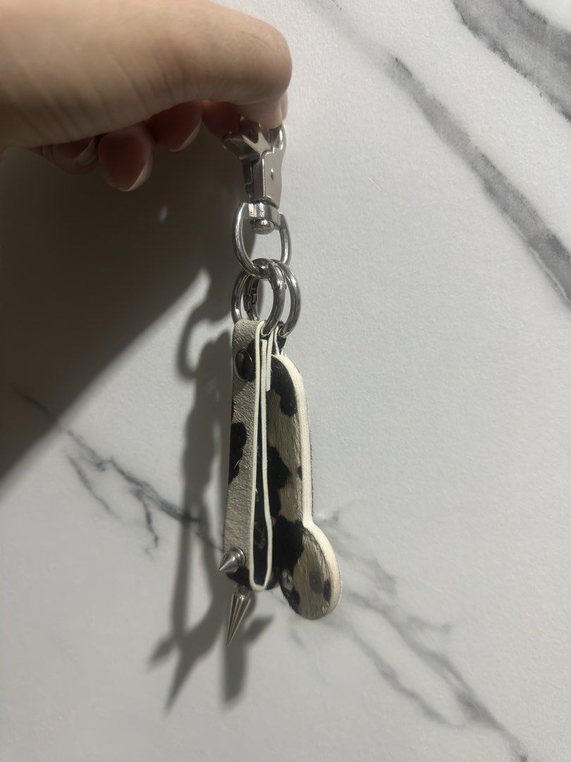 Cow print leather phallic novelty keychain with star studs (Category: Charms) located in Baguio. Submitted by miss_misery (Listing ID 1468565207, Image 2). Description: - Edgy novelty pen!s keychain and bag charm - Made in Vietnam, bought in Ho Chi Minh - Made with stylish black and white cow print leather/calf hair - Decorated with silver star studs, metal ball studs, and spike hardware - Features a built-in metal clip and split ring for keys - 