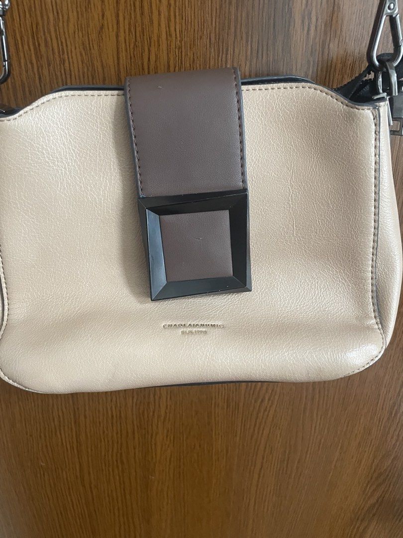 Cream and Brown Crossbody Bag (Category: Cross-body Bags) located in Manila. Submitted by misyeli (Listing ID 1468552866, Image 2). Description: - Color: Cream and brown - Closure: Structured front flap with geometric buckle accent - Branding: Gold-tone foil print near the front base - Strap: Adjustable matching shoulder strap - Pocket: Convenient snap-button pocket on the back - Condition: Brand new / Excellent (ready to ship!).