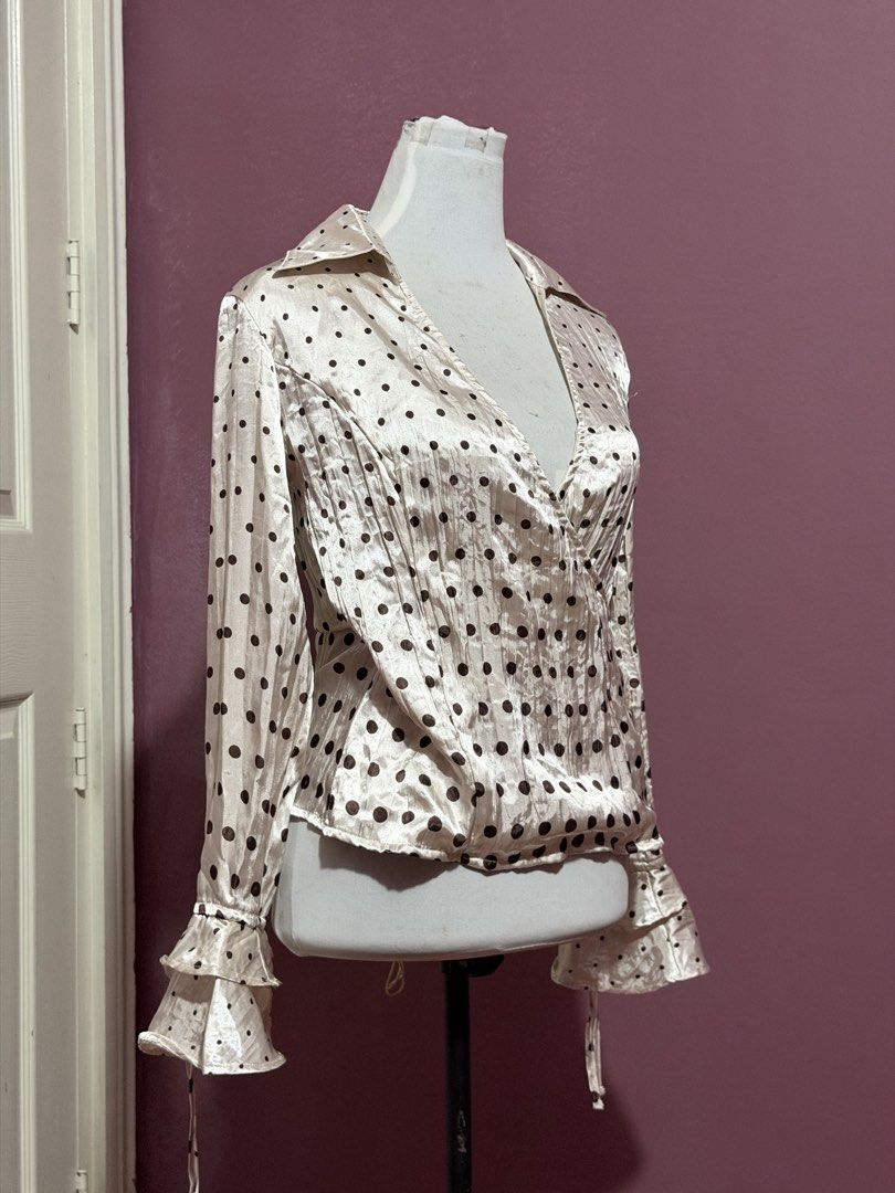 Cream Polka Dot Top Blouse with Ruffle Cuffs (Category: Blouses) located in Manila. Submitted by thatgirl0001 (Listing ID 1468592570, Image 3). Description: - Color & Pattern: Cream with all-over black polka dots - Design: Wrap front style with V-neckline and pointed collar - Sleeves: Long sleeves with double ruffle cuffs and string ties - Fabric: Lightweight silky material with a subtle vertical texture - Style: Retro vibe, easily pairs with ski