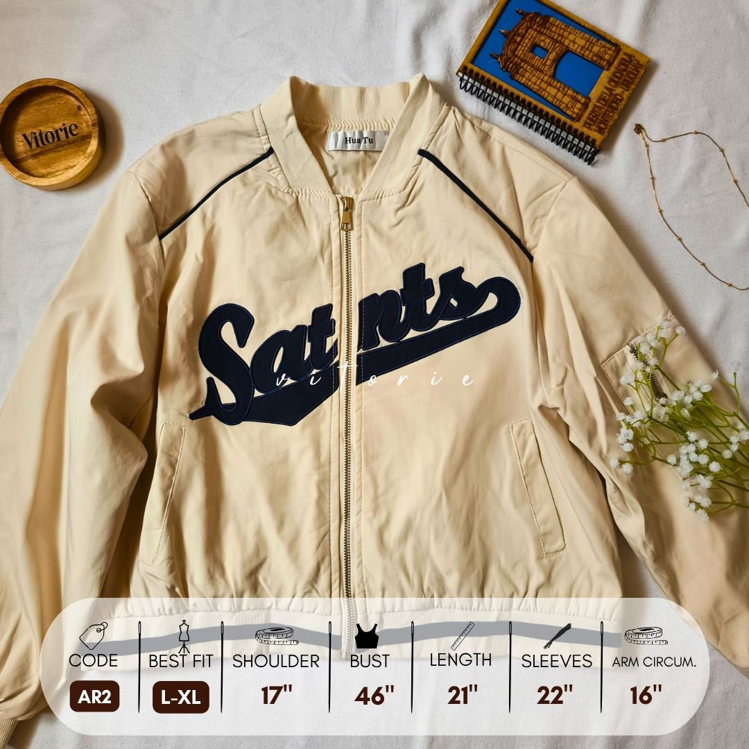 Cream Saints Bomber Jacket L-XL (Category: Coats, Jackets and Outerwear) located in Cabuyao City. Submitted by vitorieclothing_lifestyle (Listing ID 1468508692, Image 1). Description: - Cream bomber jacket with dark blue Saints script lettering - Full front gold zipper and navy shoulder piping - Features ribbed hem/cuffs and convenient side pockets - Lightweight material, ideal for layering - Size: Fits L to XL nicely - Measurements: Shoulder 17"