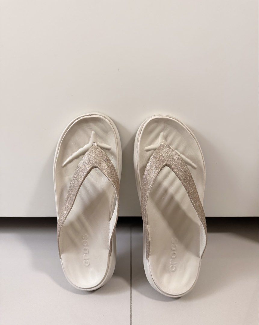 Crocs Glitter Thong Sandals Size W7 (Category: Slippers and slides) located in Quezon City. Submitted by eya_preloved (Listing ID 1468580380, Image 1). Description: - Brand: Crocs - Style: Platform flip-flops - Color: White with champagne gold sparkly straps - Size: Women's 7 - Features: Super lightweight foam footbed with textured grip - Condition: Clean footbeds, minor wear on bottom treads from brief outdoor use - Perfect for: Summer outings a