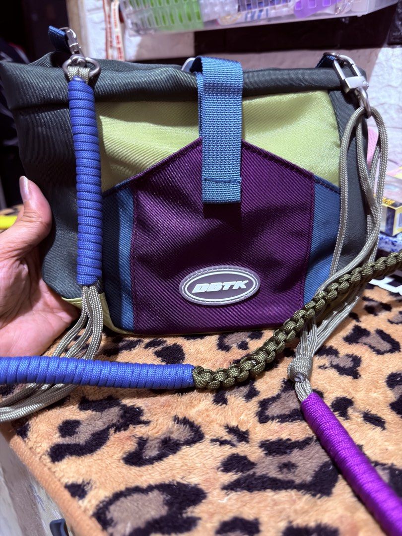 DBTK Colorblock Crossbody Bag (Category: Cross-body Bags) located in Quezon City. Submitted by auspv_collections (Listing ID 1468619952, Image 1). Description: - Brand: DBTK - Design: Colorblock (Olive Green, Blue, Yellow, Purple) - Compartments: Main zip compartment and front pocket with woven logo label - Strap: Detachable paracord-style strap with multi-colored wrapped sections - Condition: Brand new with hangtag attached - Perfect for daily s