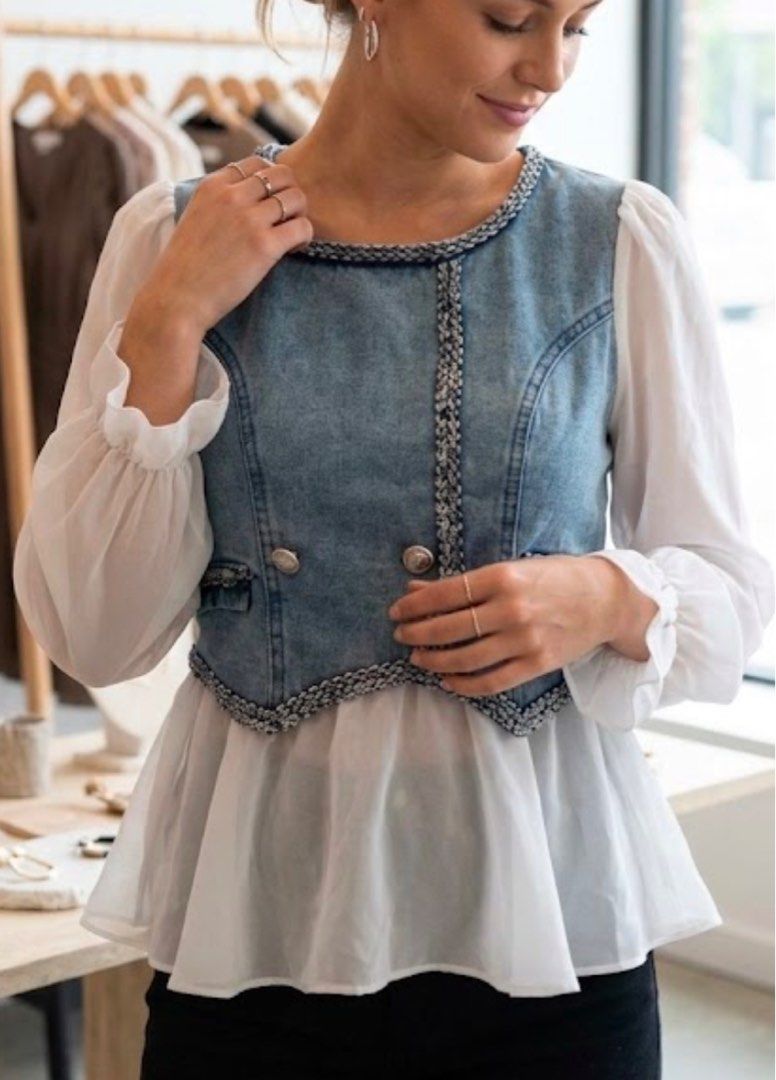 Denim Vest White Sheer Sleeve Top (Category: Sleeveless) located in Tabuk. Submitted by zenwolf-1867 (Listing ID 1463052859, Image 1). Description: - Brand new denim vest top with tags attached - Features sheer puff sleeves - Decorative trim and buttons for added style - Convenient back zipper closure - Versatile for layering or wearing solo.