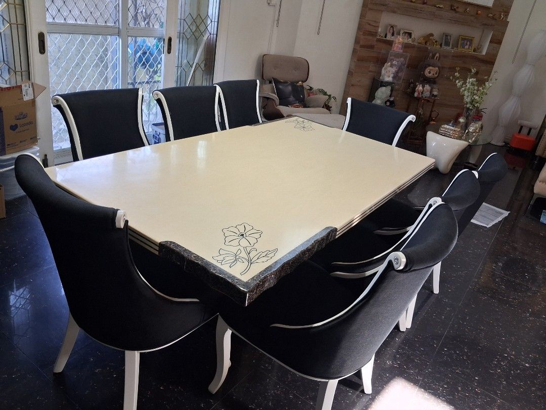 Dining table set with 8 black upholstered chairs (Category: Tables & Sets) located in Manila. Submitted by fastpenguin.445463 (Listing ID 1468549175, Image 1). Description: - Large dining table with a clean, smooth cream top - Features dark corner accents with intricate floral carvings - Includes 8 matching chairs with black fabric upholstery and white piping - Sturdy and durable build, perfect for family dinners and gatherings.