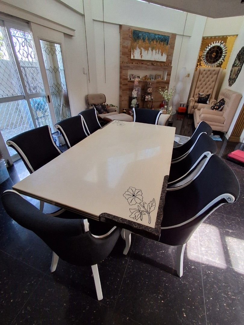 Dining table set with 8 black upholstered chairs (Category: Tables & Sets) located in Manila. Submitted by fastpenguin.445463 (Listing ID 1468549175, Image 2). Description: - Large dining table with a clean, smooth cream top - Features dark corner accents with intricate floral carvings - Includes 8 matching chairs with black fabric upholstery and white piping - Sturdy and durable build, perfect for family dinners and gatherings.